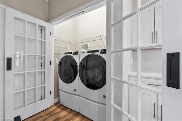 clothes washing area featuring washer and dryer, laundry area, and wood finished floors