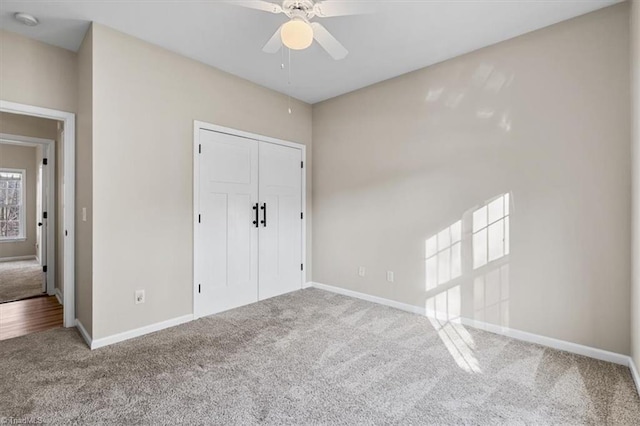 unfurnished bedroom with a closet, baseboards, carpet, and a ceiling fan