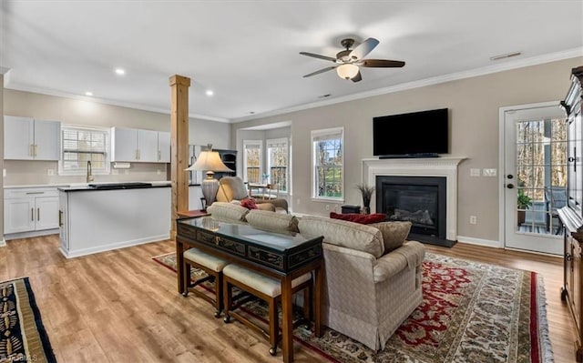 living room with light wood-style floors, a healthy amount of sunlight, ceiling fan, and ornamental molding