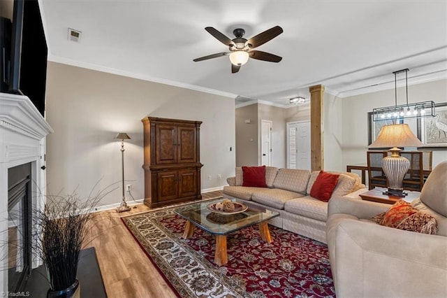 living area featuring visible vents, wood finished floors, ceiling fan, and ornamental molding