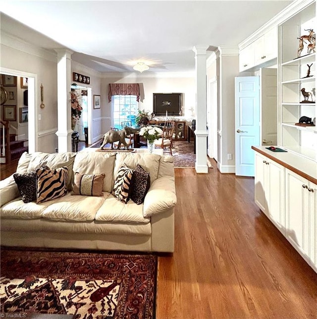 living room with ornate columns, crown molding, and dark wood-type flooring