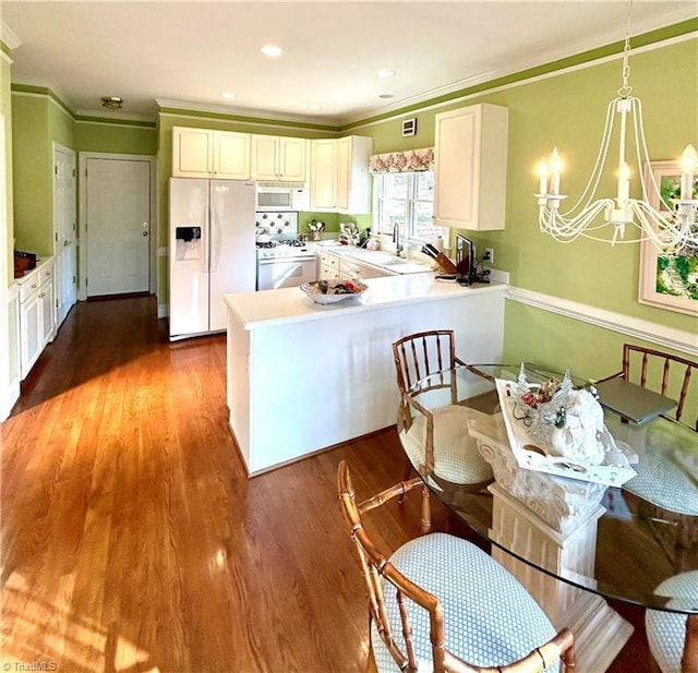 kitchen with white appliances, decorative light fixtures, hardwood / wood-style flooring, a notable chandelier, and white cabinetry