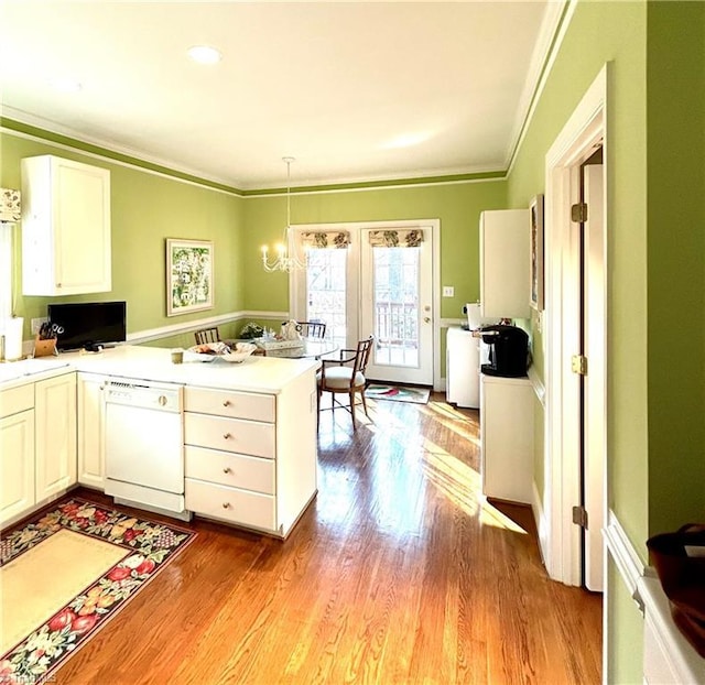 kitchen with kitchen peninsula, light wood-type flooring, white cabinets, decorative light fixtures, and dishwasher