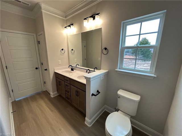 bathroom featuring vanity, wood-type flooring, ornamental molding, and toilet