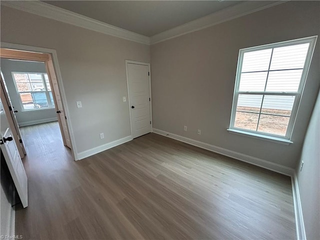 unfurnished room with crown molding, a healthy amount of sunlight, and wood-type flooring