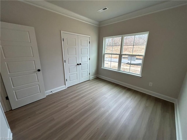 unfurnished bedroom featuring light hardwood / wood-style flooring, ornamental molding, and a closet