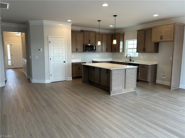 kitchen featuring pendant lighting, crown molding, a center island, and light hardwood / wood-style floors