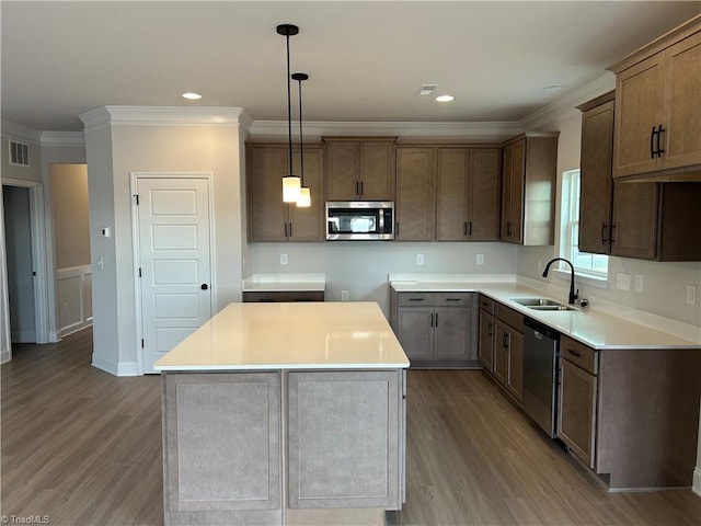 kitchen with a kitchen island, appliances with stainless steel finishes, sink, and hanging light fixtures