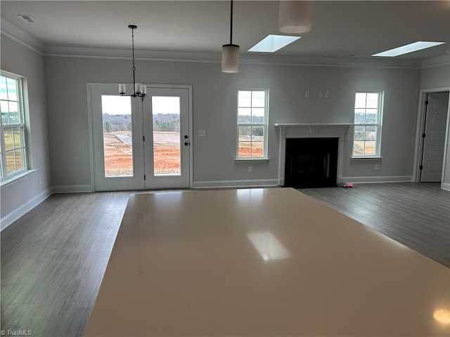 unfurnished living room with ornamental molding, a skylight, and hardwood / wood-style floors