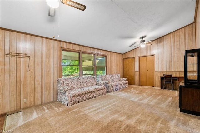 carpeted living area with ceiling fan, wood walls, and lofted ceiling