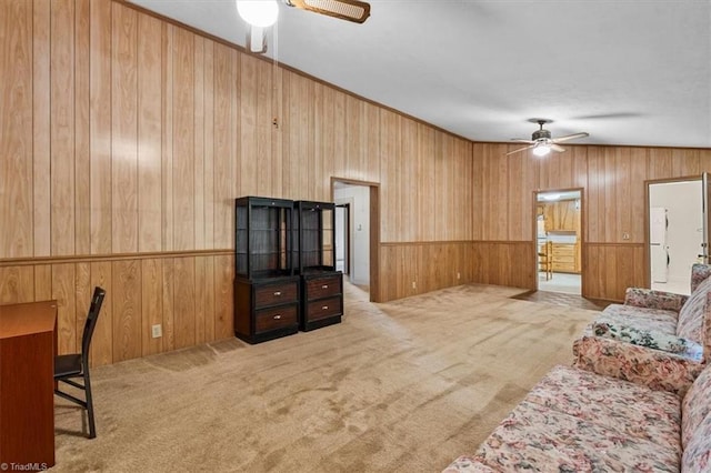 carpeted living room featuring wooden walls, a wainscoted wall, and a ceiling fan
