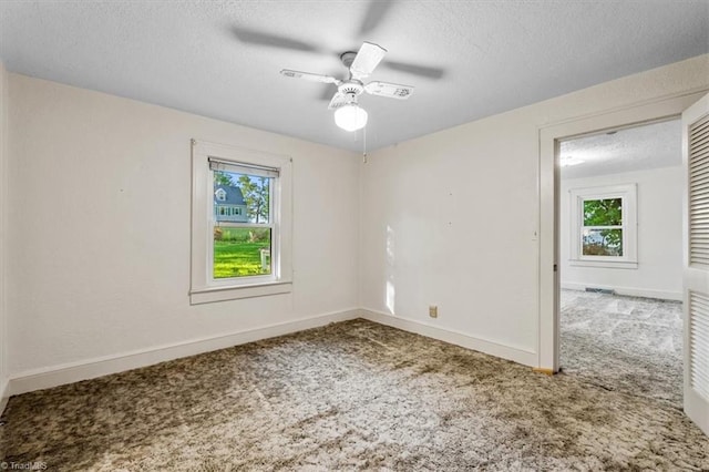 empty room with carpet floors, a textured ceiling, ceiling fan, and baseboards