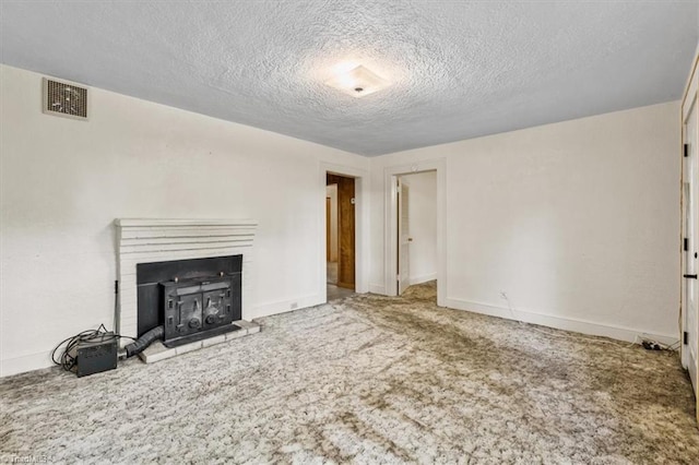unfurnished living room with a textured ceiling, visible vents, baseboards, and carpet