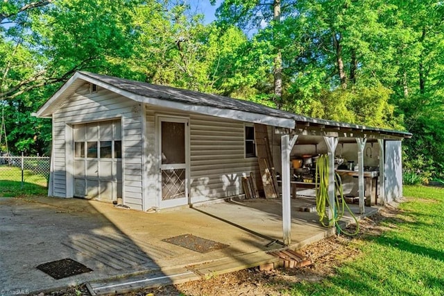 view of outdoor structure with fence and an outbuilding