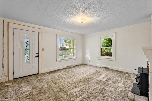 entryway featuring visible vents, carpet, a textured ceiling, and a wealth of natural light