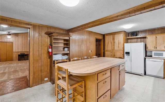kitchen with white appliances, a textured ceiling, wood walls, and ceiling fan
