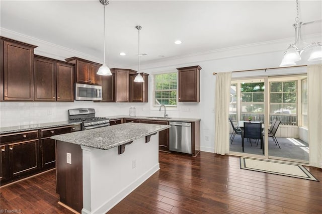 301 Summerwalk Rd, Greensboro, NC 27455 - kitchen featuring stainless steel appliances, light stone countertops, dark brown cabinetry, a kitchen island, and ornamental molding
