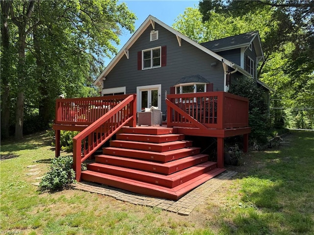back of property with a deck, a yard, and stairs