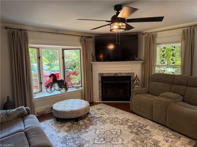 living room with a premium fireplace, ceiling fan, wood finished floors, and plenty of natural light