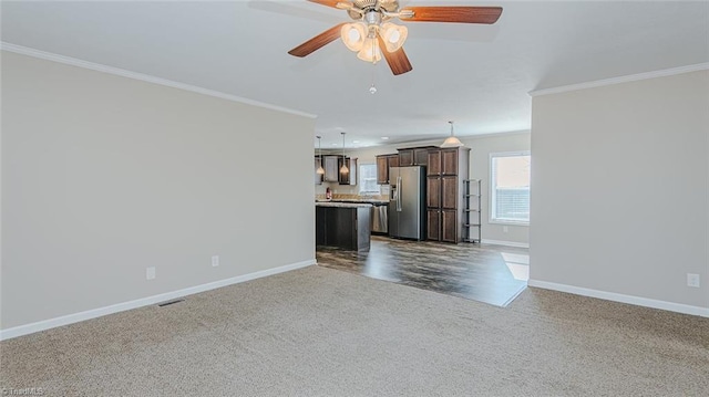 unfurnished living room featuring crown molding, ceiling fan, and dark carpet