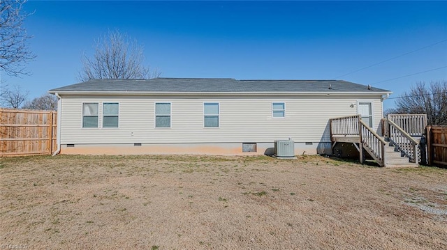 rear view of property featuring a lawn and central air condition unit