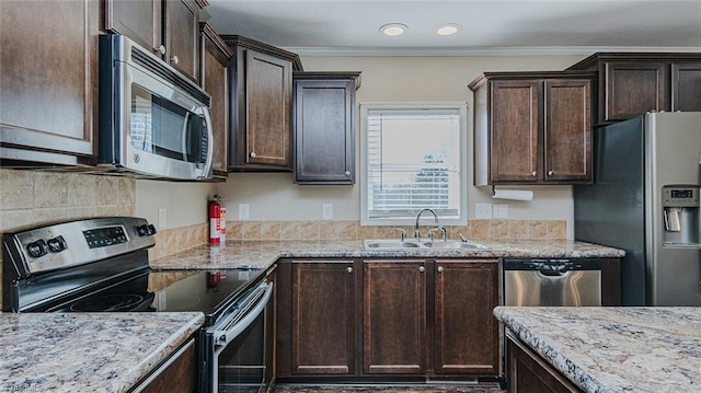 kitchen featuring sink, ornamental molding, dark brown cabinetry, stainless steel appliances, and light stone countertops