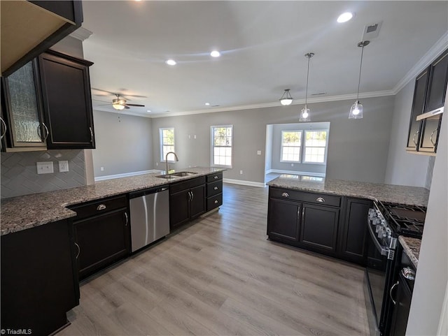 kitchen featuring pendant lighting, stainless steel dishwasher, sink, light wood-type flooring, and gas range oven