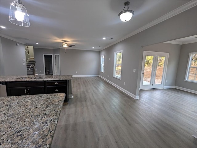 kitchen featuring open floor plan, wood finished floors, crown molding, and a sink