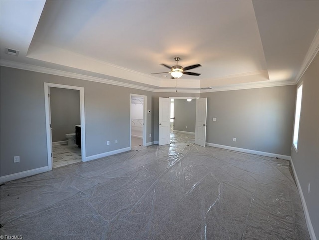 unfurnished bedroom featuring visible vents, ornamental molding, a tray ceiling, connected bathroom, and baseboards