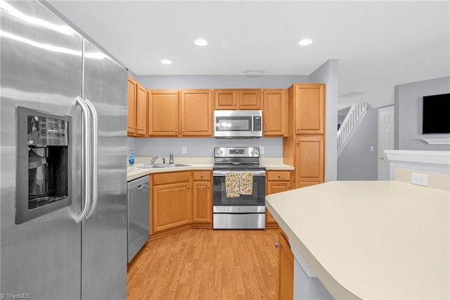 kitchen with sink, stainless steel appliances, light brown cabinets, and light wood-type flooring