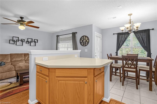 kitchen featuring pendant lighting, ceiling fan with notable chandelier, a textured ceiling, and light tile patterned flooring