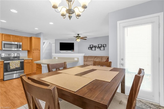 dining room with ceiling fan with notable chandelier and light hardwood / wood-style flooring