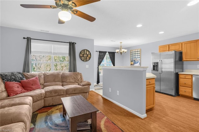 living room featuring ceiling fan with notable chandelier and light wood-type flooring