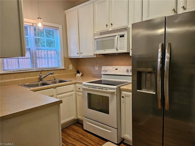 kitchen featuring dark wood-type flooring, sink, pendant lighting, white cabinetry, and white appliances