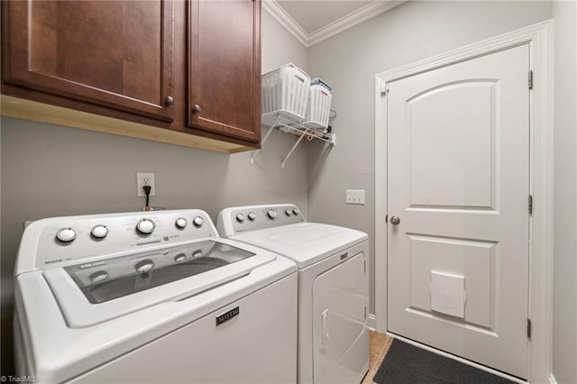 clothes washing area featuring cabinet space, washing machine and dryer, and ornamental molding