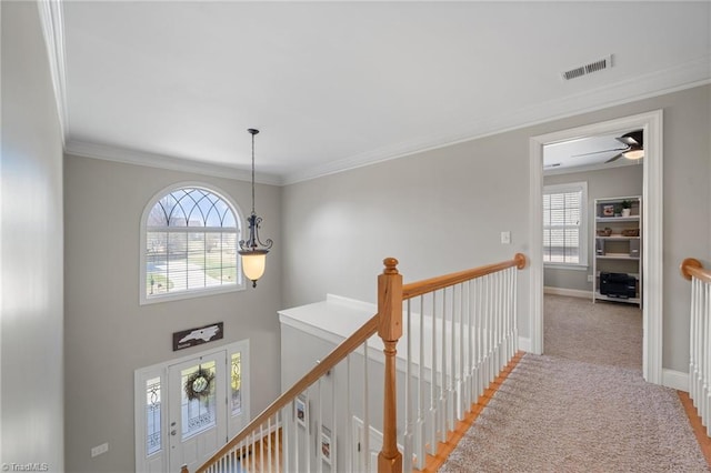 hallway with light colored carpet, an upstairs landing, visible vents, and a wealth of natural light