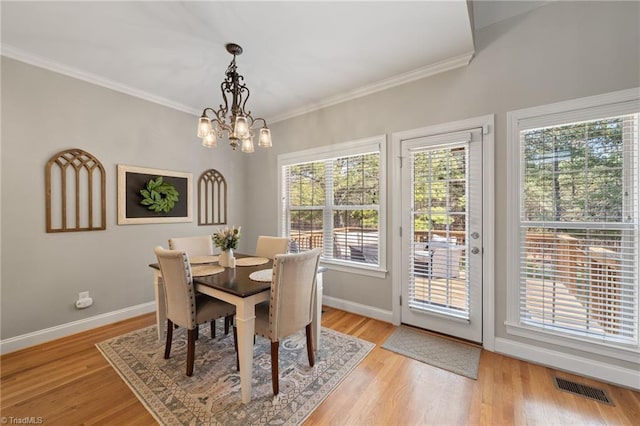 dining area with visible vents, baseboards, light wood-style floors, and crown molding