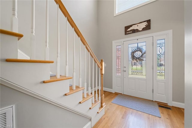 entrance foyer with wood finished floors, a healthy amount of sunlight, visible vents, and baseboards