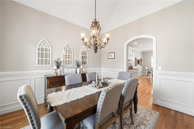 dining area with lofted ceiling, recessed lighting, wainscoting, wood finished floors, and arched walkways