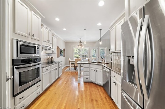 kitchen featuring under cabinet range hood, decorative backsplash, appliances with stainless steel finishes, a peninsula, and a sink