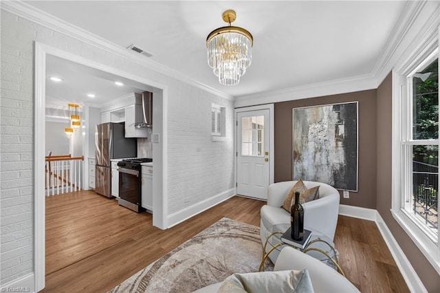 506 Audubon Dr, Greensboro, NC 27410 - living area featuring wood finished floors, a chandelier, crown molding, and brick wall