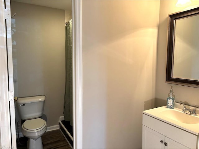 bathroom with baseboards, toilet, a shower with curtain, wood finished floors, and vanity