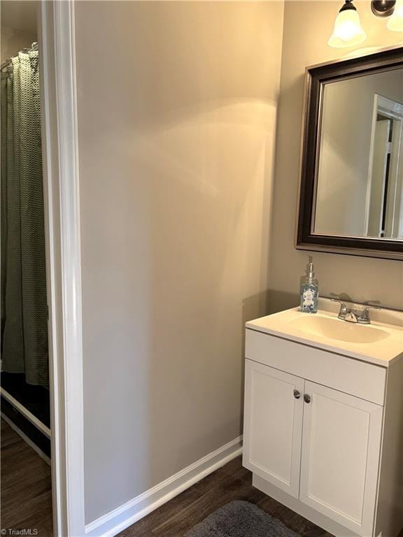 full bathroom with baseboards, wood finished floors, and vanity