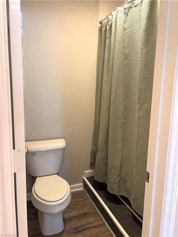 full bathroom with a shower with shower curtain, baseboards, toilet, and wood finished floors