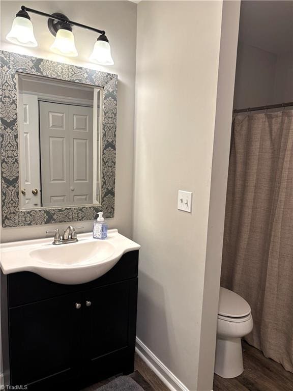 bathroom featuring toilet, wood finished floors, vanity, and baseboards