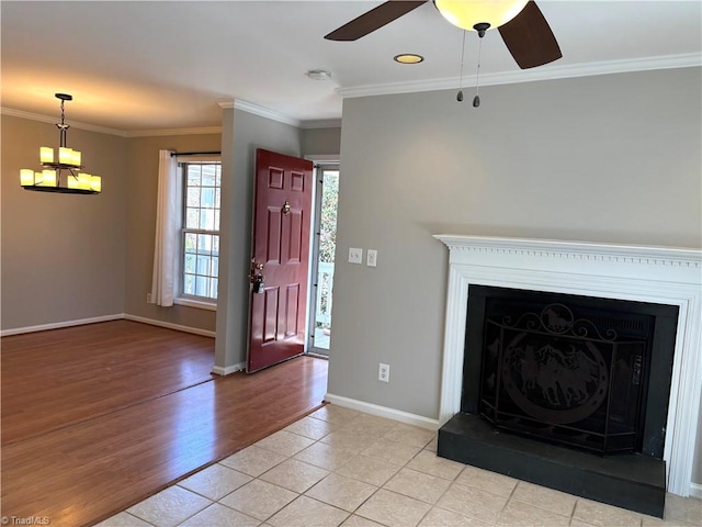 unfurnished living room featuring baseboards, ornamental molding, light wood-style floors, a fireplace, and ceiling fan with notable chandelier