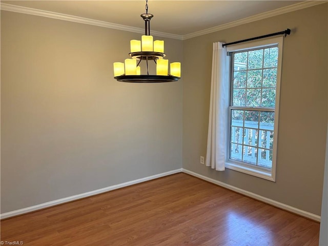 unfurnished room featuring a chandelier, crown molding, baseboards, and wood finished floors