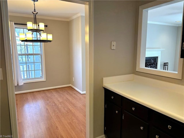 interior space featuring dark cabinets, light wood-type flooring, a chandelier, and ornamental molding