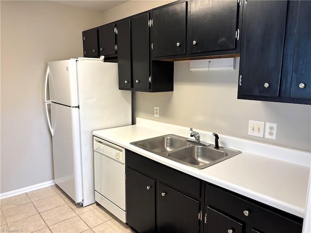 kitchen featuring a sink, white appliances, light countertops, and dark cabinetry