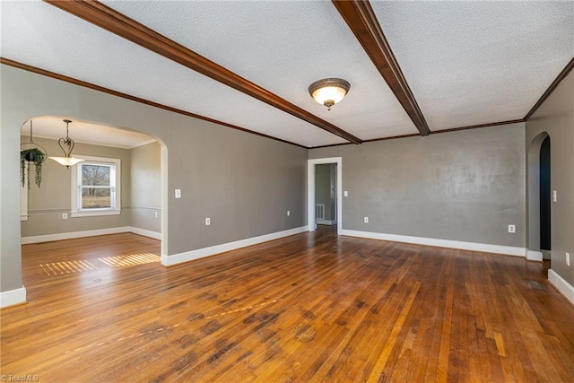 empty room featuring crown molding, wood-type flooring, beam ceiling, and a textured ceiling